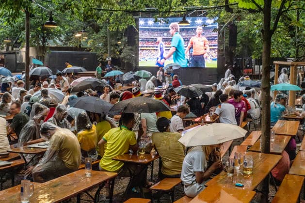 Unwetter über München: Starkes Gewitter mit Wolkenbruch beim Public Viewing im Augustinerkeller, Fußballfans beim Spiel Brasilien-Japan harren zunächst noch unter Regenschirmen aus, Fußball-WM, München, 29. Juni 2026 Deutschland, München, 29. Juni 2026, Unwetter über München: Starkes Gewitter mit Wolkenbruch beim Public Viewing im Augustinerkeller, Fußballfans beim Spiel Brasilien-Japan harren zunächst noch unter Regenschirmen aus, hier nach der Halbzeitpause um 20 Uhr, ZDF Live-Übertragung ab 19 Uht Uhr, Fußball-WM, FIFA Fußball-Weltmeisterschaft, Fußball, Sport, Gastronomie, Sommer, *** Severe Weather Over Munich: Heavy Thunderstorm with Torrential Rain at the Public Viewing Event at the Augustinerkeller; Soccer Fans Watchi