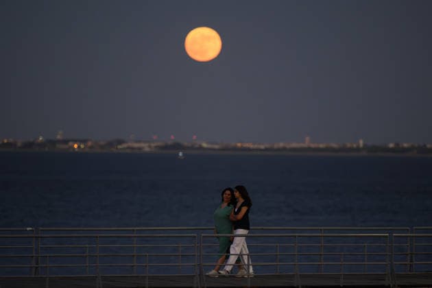 June 29, 2026, Lisbon, Portugal: People are seen walking along the banks of the Tejo River as the moon peeks over the horizon in the Lisbon sky. Strawberry Supermoon is a term derived from the traditions of the North American indigenous peoples, who called this moon by that name because it coincided with the wild strawberry harvest season. Lisbon Portugal  - ZUMAs197 20260629_aaa_s197_068 Copyright: xJorgexCastellanosx