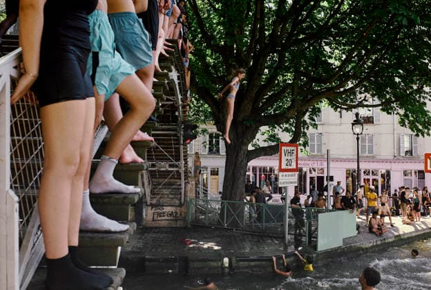 Heatwave Canal Saint Martin Paris People stand on the outer edge of a footbridge as a girl jumps from a nearby tree into the Canal Saint-Martin in Paris, France, on June 23, 2026. As France experiences a major heatwave, people use the Canal Saint-Martin as an improvised urban beach to cool off. While the city recently opened a regulated swimming area, the extreme temperatures have led many to swim in unapproved sections of the waterway. Paris Ile de France France Copyright: xOliviaxBonnamourx