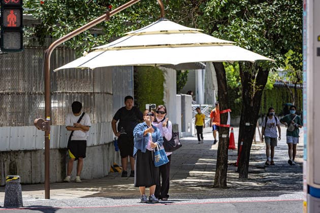 July 1, 2026, Kaohsiung City, Kaohsiung City, Taiwan: Two women use a selfie stick to take a photo together while seeking shade under a manual public street umbrella trialed at a transit pedestrian crossing in Kaohsiung, Taiwan, on July 1, 2026. Kaohsiung City Taiwan - ZUMAh198 20260701_zip_h198_006 Copyright: xCheng-ChiaxHuangx