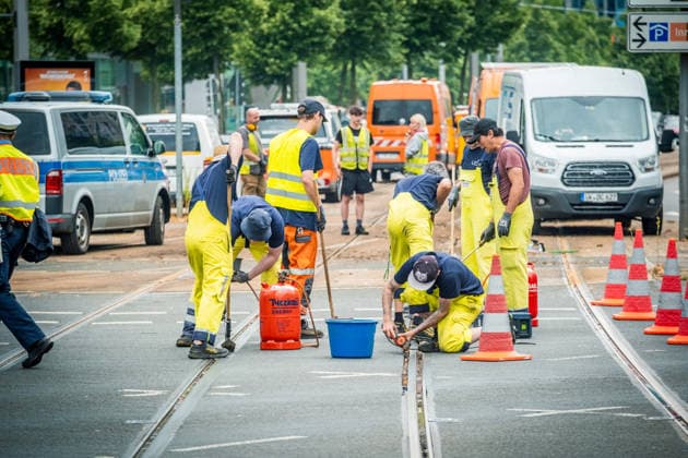 Leipziger Bürgerinnen und Bürger befreien am Johannisplatz gemeinsam mit den Leipziger Verkehrsbetrieben (LVB) die Straßenbahngleise von geschmolzenem Bitumen. Nachdem bereits am Vortag rund 100 Freiwillige einem Aufruf der LVB gefolgt waren, wurden die Reinigungsarbeiten am zweiten Tag am Johannisplatz fortgesetzt. Hintergrund sind die Schäden durch die extremen Temperaturen des vergangenen Hitzewochenendes. Aufnahme vom Datum . Reinigung Leipzig *** Residents of Leipzig are working together with the Leipzig Public Transportation Authority (LVB) to clear melted asphalt from the tram tracks at Johannisplatz. After about 100 volunteers had already responded to a call for help from the LVB the previous day, cleanup efforts continued on t
