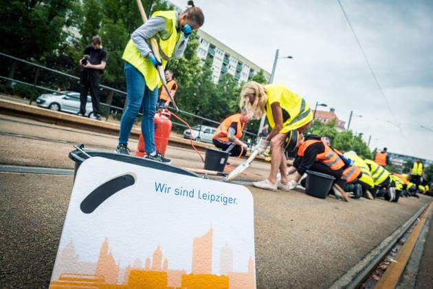 Leipziger Bürgerinnen und Bürger befreien am Johannisplatz gemeinsam mit den Leipziger Verkehrsbetrieben (LVB) die Straßenbahngleise von geschmolzenem Bitumen. Nachdem bereits am Vortag rund 100 Freiwillige einem Aufruf der LVB gefolgt waren, wurden die Reinigungsarbeiten am zweiten Tag am Johannisplatz fortgesetzt. Hintergrund sind die Schäden durch die extremen Temperaturen des vergangenen Hitzewochenendes. Aufnahme vom Datum . Reinigung Leipzig *** Residents of Leipzig are working together with the Leipzig Public Transportation Authority (LVB) to clear melted asphalt from the tram tracks at Johannisplatz. After about 100 volunteers had already responded to a call for help from the LVB the previous day, cleanup efforts continued on t