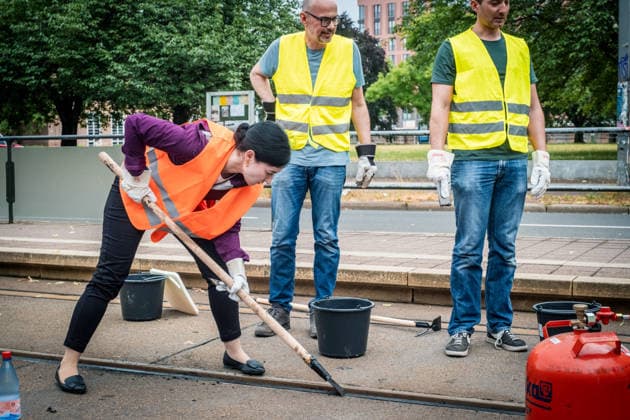 Leipziger Bürgerinnen und Bürger befreien am Johannisplatz gemeinsam mit den Leipziger Verkehrsbetrieben (LVB) die Straßenbahngleise von geschmolzenem Bitumen. Nachdem bereits am Vortag rund 100 Freiwillige einem Aufruf der LVB gefolgt waren, wurden die Reinigungsarbeiten am zweiten Tag am Johannisplatz fortgesetzt. Hintergrund sind die Schäden durch die extremen Temperaturen des vergangenen Hitzewochenendes. Aufnahme vom Datum . Reinigung Leipzig *** Residents of Leipzig are working together with the Leipzig Public Transportation Authority (LVB) to clear melted asphalt from the tram tracks at Johannisplatz. After about 100 volunteers had already responded to a call for help from the LVB the previous day, cleanup efforts continued on t