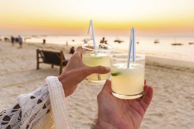Nahaufnahme, Sonnenuntergang beobachten, Cocktails halten, feiern, Toast am tropischen Sandstrand von Sansibar bei Sonnenuntergang machen, Urlaubsreisen, romantischer Urlaubsresort, Luxus, Sommerurlaub, Getränk, Entspannung Close up couple watch sunset holding cocktails celebrate make toast on tropical Zanzibar sandy beach during sunset, leisure travel, romantic vacation resort luxury, summer holiday beverage relaxation Copyright: imageBROKER EvaldasxMikoliunas ibxemi18230926.jpg ,model released, Symbolfoto ,property released