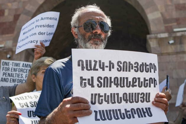 ARMENIA, YEREVAN - JULY 2, 2026: Protesters are seen outside the Government House amid talks between European Commission President von der Leyen and Armenia s President Pashinyan. The message on the sign reads: One-time amnesty for penalties and fines of the Compulsory Enforcement Service . Alexander Patrin TASS  94569769