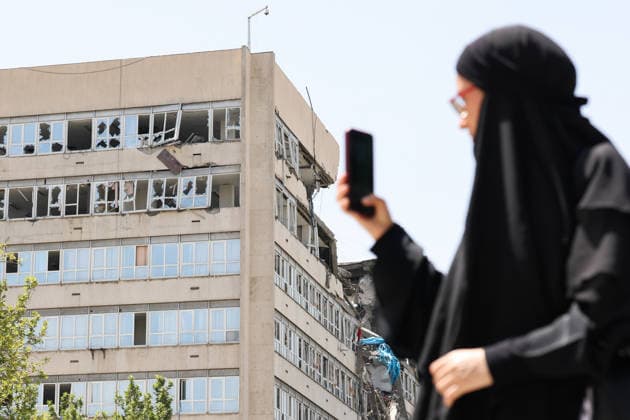 IRAN, TEHRAN - JULY 3, 2026: A woman walks past a damaged local government building on the eve of the state funeral of Supreme Leader Ali Khamenei (1939-2026) set to take place from July 4 to 9. Khamenei was killed in a joint US-Israeli airstrike on his residence on February 28 Tehran Iran  - ZUMAt113 20260703_zaa_t113_023 Copyright: xValeryxSharifulinx