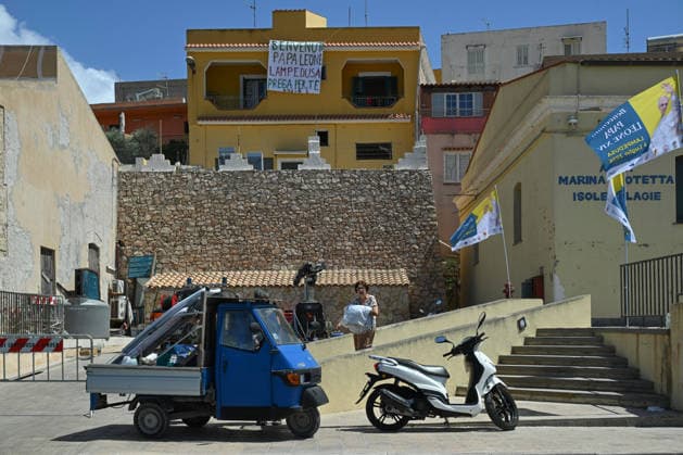 Daily life in Lampedusa before the arrival of Pope Leo XIV LAMPEDUSA, ITALY - JULY 3: Local residents hold a banner to welcome Pope Leo XIV ahead of his visit to Lampedusa on July 4, as local residents, security forces and NGOs prepare to receive the pontiff while tourists and locals continue their daily summer activities in Lampedusa, Italy, on July 3, 2026. Valeria Ferraro Anadolu Lampedusa Italy. Editorial use only. Please get in touch for any other usage.  Copyright: x2026xAnadoluxValeriaxFerrarox