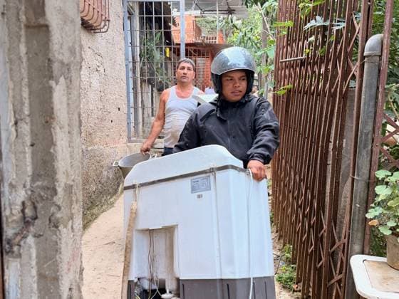 One person injured after partial collapse of school building in La Pastora, Venezuela CARACAS, VENEZUELA - JULY 3: Two men are carrying a twin-tub washing machine down a narrow, dusty alley near where the walls of San Judas Tadeo High School collapsed in La Pastora, Caracas, Venezuela, on July 3, 2026. The man in front, wearing a helmet, is carrying the machine, while the man behind him helps, also carrying a metal pot. In the background, metal fences and vegetation are visible. Part of the Agustiniano San Judas Tadeo School building, collapsed on the afternoon of Friday, nine days after the country was struck by a double earthquake. Although the building had been evacuated due to severe damage, one person was injured. Julio Urribarri Ana  Copyright: x2026xAnadoluxJulioxUrribarrix