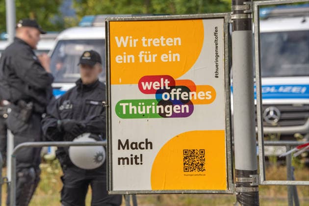 Plakat Wir treten ein für ein weltoffenes Thüringen, im Hintergrund: Polizei riegelt das Messegelände ab, wo der AfD-Parteitag stattfindet, Plakat bei der Hauptkundgebung gegen den AfD-Bundesparteitag an diesem Wochenende, Erfurt, 4. Juli 2026 Deutschland, Erfurt, 4. Juli 2026, Plakat Wir treten ein für ein weltoffenes Thüringen, im Hintergrund: Polizei riegelt das Messegelände ab, wo der AfD-Parteitag stattfindet, Plakat bei der Hauptkundgebung gegen den AfD-Bundesparteitag an diesem Wochenende in Erfurt, Kundgebung organisiert vom DGB und dem Bündnis Zusammenstehen, Zehntausende protestieren an der Messe Erfurt, wo der AfD Parteitag stattfindet, Protestbewegung, Politik, Thüringen *** Poster: We stand for a cosmopolitan Thuringi