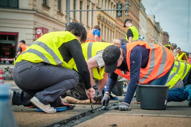 Freiwillige Helfer reinigen gemeinsam mit Mitarbeitenden der Leipziger Verkehrsbetriebe (LVB) Straßenbahngleise an der Leibnizstraße in Leipzig (Sachsen) von geschmolzenem Bitumen. Die Arbeiten sind Teil eines dritten Subbotniks zur Beseitigung der Hitzeschäden am Straßenbahnnetz. Aufnahme vom 4. Juli 2026. Hilfsaktion Leipzig *** Volunteers are working alongside employees of the Leipzig Public Transportation Authority (LVB) to clean melted bitumen from the tram tracks on Leibnizstraße in Leipzig, Saxony. The work is part of a third subbotnik aimed at repairing heat damage to the tram network. Photo taken on July 4, 2026. VolunteerLeipzig Relief Effort