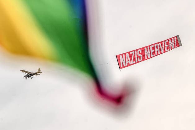 Flugzeug kreuzt am Himmel mit Protesttransparent Nazis nervern, Regenbogenflagge weht ins Bild, bei Hauptkundgebung gegen den AfD-Bundesparteitag an diesem Wochenende, DGB und Bündnis Zusammenstehen, Erfurt, 4. Juli 2026 Deutschland, Erfurt, 4. Juli 2026, Flugzeug kreuzt am Himmel mit Protesttransparent Nazis nervern, Regenbogenflagge weht ins Bild, bei der Hauptkundgebung gegen den AfD-Bundesparteitag auf dem Erfurter Messegelände, Kundgebung organisiert vom DGB und dem Bündnis Zusammenstehen, Zehntausende protestieren an der Messe Erfurt, wo der AfD Parteitag stattfindet, Protestbewegung, Politik, Thüringen *** Airplane flies across the sky with a protest banner to annoy Nazis; a rainbow flag flutters into the frame during the main