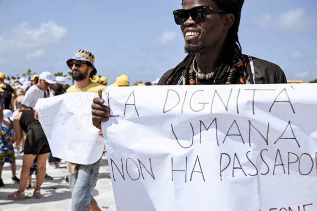Pope Leo XIV visits the Southern Italian island of Lampedusa LAMPEDUSA, ITALY - JULY 04: A boy from Palermo Baye Fall with a placard quoting Human dignity has no passport in Lampedusa, Italy, on July 04, 2026. Pope Leo XIV arrived in Lampedusa to rise attention to the migrant issue and the unique position of the island. During his visit he met with a group of migrants, accompanied by the Red Cross at Favaloro Pier, inaugurating a new plaque with the new name of the Pier dedicated to Pope Francis. Later nearly 4000 people gathered in the sport field to attend the homily celebrated by the Pope. Valeria Ferraro Anadolu Lampedusa Italy. Editorial use only. Please get in touch for any other usage.  Copyright: x2026xAnadoluxValeriaxFerrarox