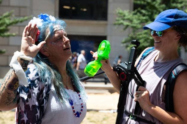 March against Trump on Independence Day in Washington, DC WASHINGTON, D.C., USA JULY 4, 2026: A woman cools a fellow demonstrator during We The People 250, a march against abuse of power by U.S. President Donald Trump and his administration. The march ended early due to record heat in the nation™s capital. WASHINGTON, D.C. DC United States of America Copyright: x xAllisonxBaileyx xJNAxPressx