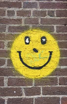 Exeter England: Gelbes Smiley Graffiti auf einer roten Backsteinmauer mit einigen geringfügigen Lackschäden und Gebrauchsspuren Exeter-England: Yellow smiley face graffiti painted on a red brick wall with some minor paint damage and wear Copyright: imageBROKER dynamixx ibxdlb18205047.jpg