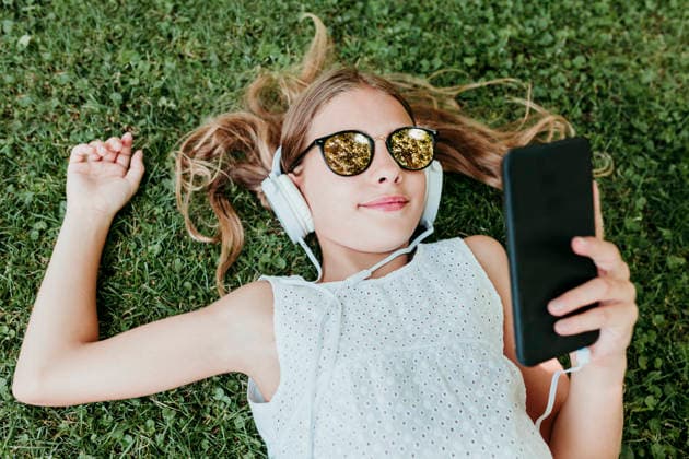 Girl wearing sunglasses lying on grass in summer model released, Symbolfoto, EBBF03754
