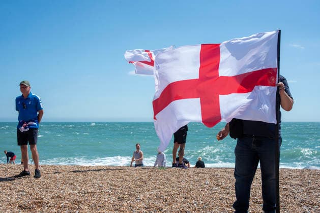 July 4, 2026, Dover, United Kingdom: A far-right activist holds a St George s flag during a demonstration on the beach outside the Immigration Centre in Dover. Around 100-120 supporters of the Pink Ladies gathered from across the country in Dover, UK. The Pink Ladies is an anti immigration far-right movement. The far-right activists marched through central Dover to the Immigration Centre and they were confronted by a small group of antifascist counter-protesters during their march. Dover United Kingdom - ZUMAs197 20260704_aaa_s197_227 Copyright: xKrisztianxElekx