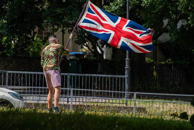 July 4, 2026, Dover, United Kingdom: A far-right protester wave a Union Jack at the roundabout before a demonstration in Dover. Around 100-120 supporters of the Pink Ladies gathered from across the country in Dover, UK. The Pink Ladies is an anti immigration far-right movement. The far-right activists marched through central Dover to the Immigration Centre and they were confronted by a small group of antifascist counter-protesters during their march. Dover United Kingdom - ZUMAs197 20260704_aaa_s197_233 Copyright: xKrisztianxElekx
