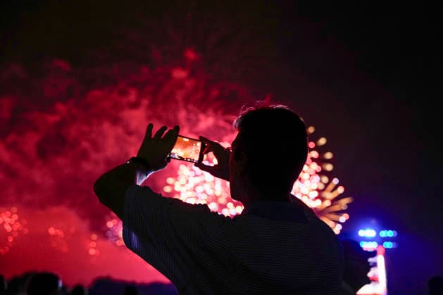 A spectator takes pictures as fireworks light up the night sky over the National Mall as part of the America 250 celebrations in Washington DC on Saturday, July 4, 2026. The 35 minute July 4 fireworks show will feature 850,000 fireworks and pyrotechnic effects.  WAP20260704920 BONNIExCASH