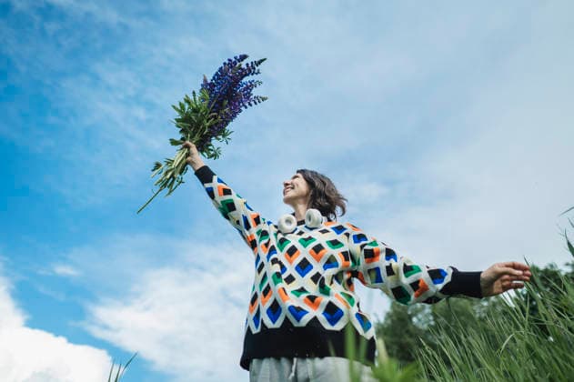 Joyful woman raises a lupine bouquet in a field model released, Symbolfoto, ANAF06148