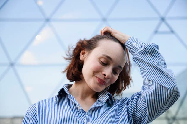 Smiling businesswoman touches her hair outside the modern office model released, Symbolfoto, EYAF04263