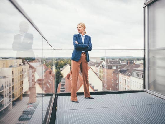 Thoughtful businesswoman with arms crossed standing on balcony model released, Symbolfoto property released, JOSEF06606