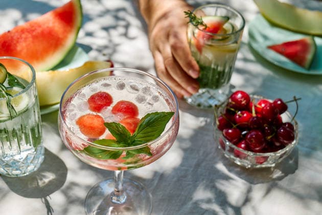 A man holds a refreshing summer cocktail at an outdoor dining table model released, Symbolfoto, CATF01066