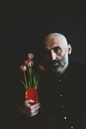 Mature man holding flower vase against black background model released, Symbolfoto property released, JOSEF19091