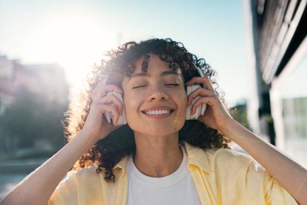 Smiling woman listens to music on headphones outdoors in the city model released, Symbolfoto, JSRF04525