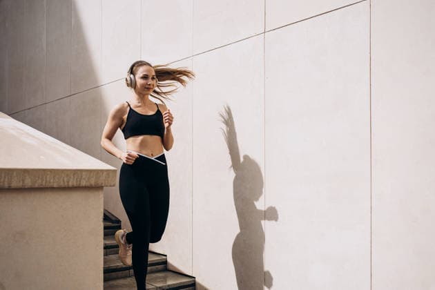 Sporty woman runs up outdoor stairs listening to music model released, Symbolfoto, KANF00245