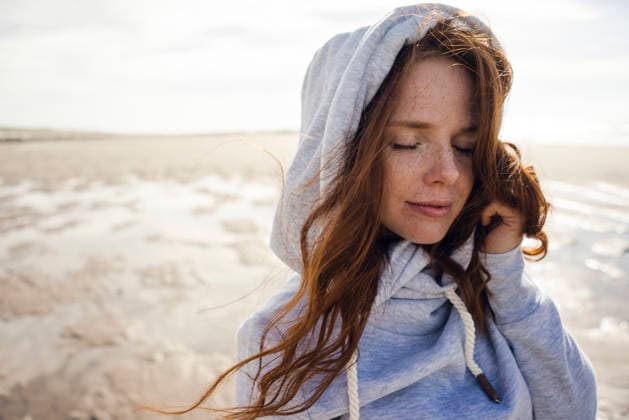 Netherlands, Zeeland, portrait of redheaded woman with freckles wearing hooded jacket on the beach model released, Symbolfoto, KNSF04197