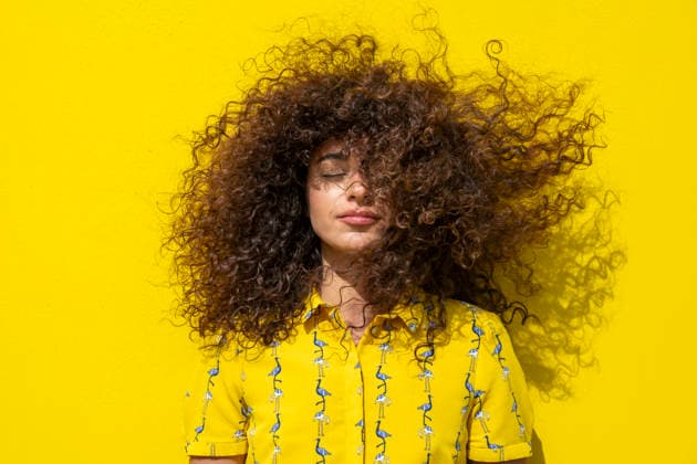 Curly hair blowing in the wind against a yellow background model released, Symbolfoto, LMCF02983