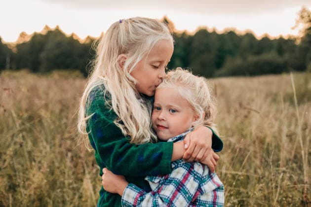 A blonde girl hugs and kisses her sister in a summer meadow model released, Symbolfoto, NASF00281
