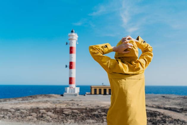Woman in yellow raincoat looks at a lighthouse in Tenerife model released, Symbolfoto, NDEF03366