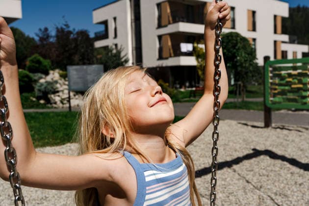 A happy child enjoys a swing in a modern housing courtyard model released, Symbolfoto, NSTF00621