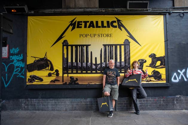 Metallica fans by the pop up ship in London, UK - 5Jul 2026 Two fans pose for a photo front of a Metallica banner outside the pop up shop in London. Metallica heavy metal band is having two concerts in London over the weekend as part of the M72 World Tour. Hundreds of Metallica fans were seen queuing up to buy some memorabilia by the Metallica pop up shop which is open for 4 days in London, UK. London United Kingdom Copyright: xKrisztianxElekx xSOPAxImagesx SSS_20260705_POPUP_SHOP_0011005008
