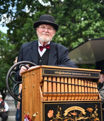(260706) -- BERLIN, July 6, 2026 -- A player poses for photos with his barrel organ in Berlin, Germany, July 5, 2026. The International Barrel Organ Festival 2026 was held in Berlin from July 3 to 5. Barrel organ players from across the world gathered here to entertain residents and visitors with a nostalgic musical celebration. ) GERMANY-BERLIN-BARREL ORGAN FESTIVAL ZhangxHaofu 