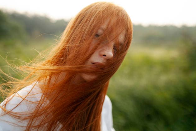 Woman stands in reeds with red hair blowing in the golden sun model released, Symbolfoto, VCF01669