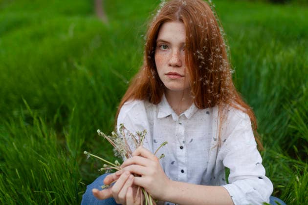 A teenager with red hair holds dandelions in the green grass model released, Symbolfoto, VCF01713