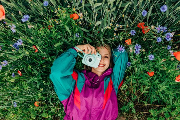 Woman in retro tracksuit holds camera on grass outdoors model released, Symbolfoto, VSNF05147