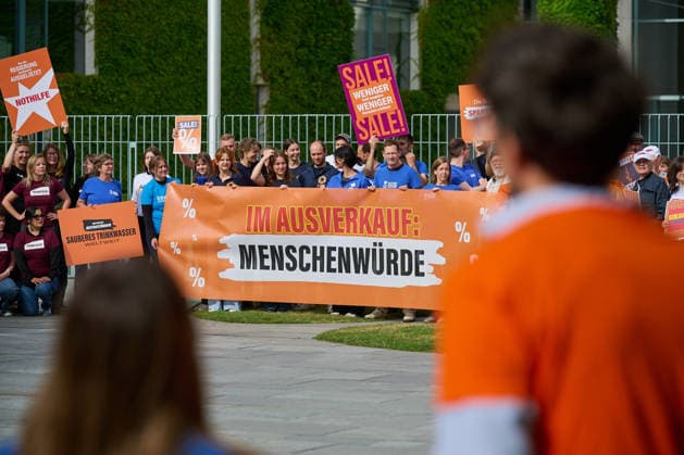 Ein Buendnis aus 15 Hilfsorganisationen protestiert am Montag (06.07.2026) vor dem Bundeskanzleramt in Berlin gegen Kuerzungen in der Entwicklungszusammenarbeit. Bei der Aktion Menschenwuerde im Ausverkauf fordern die Organisationen Aenderungen im Bundeshaushalt 2027. Dem Buendnis gehoeren unter anderem Brot fuer die Welt, misereor, Oxfam Deutschland sowie die Welthungerhilfe an. (Siehe epd-Meldung vom 06.07.2026) EDITORIAL USE ONLY *** A coalition of 15 aid organizations will protest on Monday, July 6, 2026, in front of the Federal Chancellery in Berlin against cuts to development cooperation. As part of the campaign Human Dignity on Sale, the organizations are calling for changes to the 2027 federal budget. The coalition includesinclu Copyright: epd-bild ChristianxDitsch epd-Protest_Kuerzungen3-kopieren