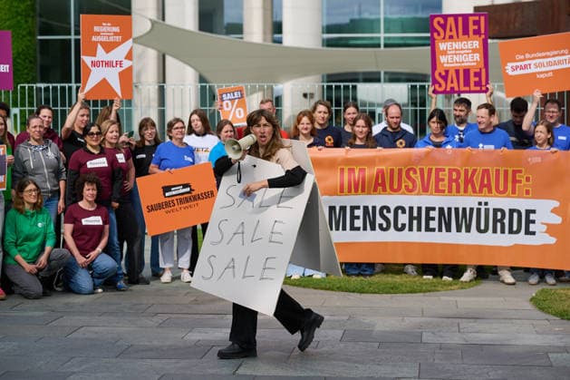 Ein Buendnis aus 15 Hilfsorganisationen protestiert am Montag (06.07.2026) vor dem Bundeskanzleramt in Berlin gegen Kuerzungen in der Entwicklungszusammenarbeit. Bei der Aktion Menschenwuerde im Ausverkauf fordern die Organisationen Aenderungen im Bundeshaushalt 2027. Dem Buendnis gehoeren unter anderem Brot fuer die Welt, misereor, Oxfam Deutschland sowie die Welthungerhilfe an. (Siehe epd-Meldung vom 06.07.2026) EDITORIAL USE ONLY *** A coalition of 15 aid organizations will protest on Monday, July 6, 2026, in front of the Federal Chancellery in Berlin against cuts to development cooperation. As part of the campaign Human Dignity on Sale, the organizations are calling for changes to the 2027 federal budget. The coalition includesinclu Copyright: epd-bild ChristianxDitsch epd-Protest_Kuerzungen4-kopieren