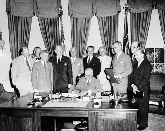 RECORD DATE NOT STATED Photo of NATO Founding Meeting Photograph of the founding meeting of NATO in 1949, where political leaders gather around a seated man signing a document in a formal office setting. Editorial use only. All other uses to be cleared with the copyright owner (World History Archive), in advance., WHA_298_0120.jpg, NATO; North Atlantic Treaty Organisation; 1949; Founding Meeting; Cold War; Post-World War II; International Security; Collective Defense; Military Alliance; Diplomacy; United States; United Kingdom; France; Canada; Belgium; Netherlands; Western Alliance; Geopolitical Strategy; Harry S Truman; Dean Acheson Copyright: xWorldxHistoryxArchivex