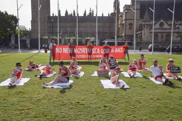 July 7, 2026, London, England, United Kingdom: Climate activists from the group Fossil Free London don swimming costumes and stage a Ã¢â‚¬Ëœsunbathe-inÃ¢â‚¬â ¢ protest dubbed Roast Against Rosebank in Parliament Square calling on the government to stop new North Sea oil and gas projects, as another heatwave hits the UK. London United Kingdom - ZUMAv130 20260707_zip_v130_001 Copyright: xVukxValcicx