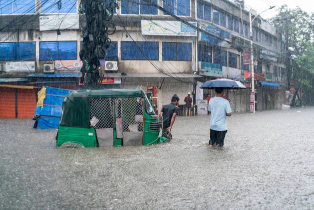 Bangladesh: Severe Waterlogging Paralyzes Chattogram Amid Heavy Monsoon Rain In Chattogram A man pushes a stranded CNG auto-rickshaw through deep rainwater while another pedestrian walks with an umbrella during a heavy monsoon shower in Chattogram, Bangladesh, on July 7, 2026. The flash urban flooding causes numerous vehicles to break down on key city roads. Chattogram Bangladesh  Copyright: xZakirxHossainx originalFilename: hossain-notitle260707_npcys.jpg
