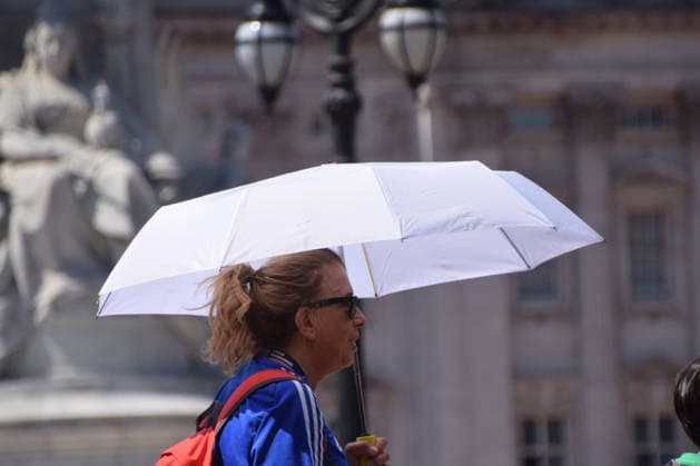 UK Weather: heatwave in London, UK - 8 Jul 2026 A woman carries an umbrella to shield herself from heat as she walks outside Buckingham Palace. London United Kingdom Copyright: xVukxValcicx xSOPAxImagesx VukValcicHeatwave080726_10