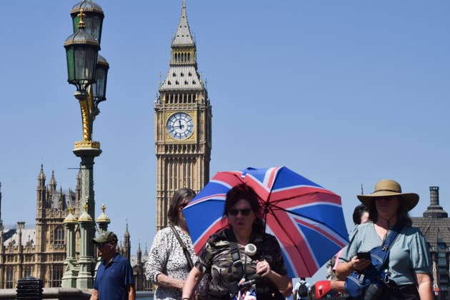 UK Weather: heatwave in London, UK - 8 Jul 2026 A woman carries an umbrella to shield herself from heat as she walks on Westminster Bridge. London United Kingdom Copyright: xVukxValcicx xSOPAxImagesx VukValcicHeatwave080726_9