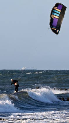 20260708 Strandidylle an der Ostsee bei Börgerenede-Rethwisch, einer Gemeinde im Landkreis Rostock in Mecklenburg-Vorpommern. Touristen und Urlauber flannieren am Strand, sitzen in Campingstühlen, bauen Sandburgen und suchen Bernstein. Sogar Kitesurfer gehen bei dem Wellengang auf dem Wasser ihrem Sport nach. Börgerende-Rethwisch Mecklenburg-Vorpommern Deutschland *** 20260708 A picturesque beach scene on the Baltic Sea near Börgerende Rethwisch, a municipality in the Rostock district of Mecklenburg-Western Pomerania. Tourists and vacationers stroll along the beach, sitting in camping chairs, building sandcastles, and searching for amber. Even kitesurfers are enjoying their sport on the water amid the waves. Börgerende Rethwisch, Mec