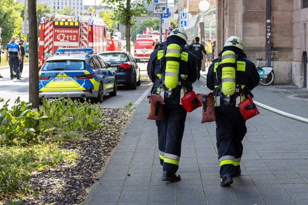 Feuerwehr-Großeinsatz am Nürnberger Opernhaus nach Brand in Tiefgarage, Nürnberg, 09.07.2026 Zwei Atemschutzträger der Feuerwehr Nürnberg - darunter Kräfte der Freiwilligen Feuerwehr - laufen mit Ausrüstung zum Einsatzort. Ein brennendes Auto hatte in einer Tiefgarage ein Feuer ausgelöst, das auf weitere Fahrzeuge übergriff. Starke Rauchentwicklung aus Lüftungsschächten erschwert den Einsatz; das angrenzende Staatstheater wurde evakuiert. Nürnberg Bayern Deutschland *** Large-Scale Fire Department Operation at the Nuremberg Opera House Following a Fire in an Underground Parking Garage, Nuremberg, July 9, 2026 Two firefighters from the Nuremberg Fire Department, including members of the volunteer fire department, are running to 20260709-286A1378-M4000