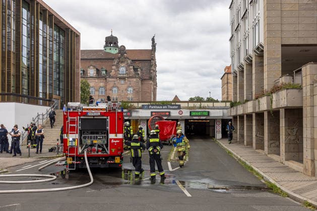Feuerwehr-Großeinsatz am Nürnberger Opernhaus nach Brand in Tiefgarage, Nürnberg, 09.07.2026 Feuerwehrkräfte im Einsatz vor der Einfahrt des Parkhaus am Theater nach einem Fahrzeugbrand in der Tiefgarage. Ein brennendes Auto hatte das Feuer ausgelöst, das auf weitere Fahrzeuge übergriff. Die starke Rauchentwicklung erforderte die Evakuierung des angrenzenden Staatstheaters Nürnberg; hinzugezogene Statiker prüfen die Standsicherheit der Tiefgarage. Nürnberg Bayern Deutschland *** Major Fire Department Operation at the Nuremberg Opera House Following a Fire in the Underground Parking Garage, Nuremberg, July 9, 2026 Firefighters on the scene in front of the entrance to the theater’s parking garage following a vehicle fire in the un 20260709-286A1435-M4000