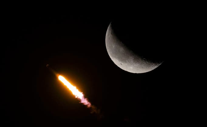 The SpaceX Falcon 9 rocket races past a crescent moon as it launches on mission 10-42 at 5.25 AM from Launch Complex 40 at the Cape Canaveral Space Force Station, Florida on Thursday July 9, 2026. Launching on SpaceX s most flown booster, B1067 which has 35 previous missions; 29 Broadband satellites will be flown into low earth orbit.  CCP20260709004 JOExMARINO